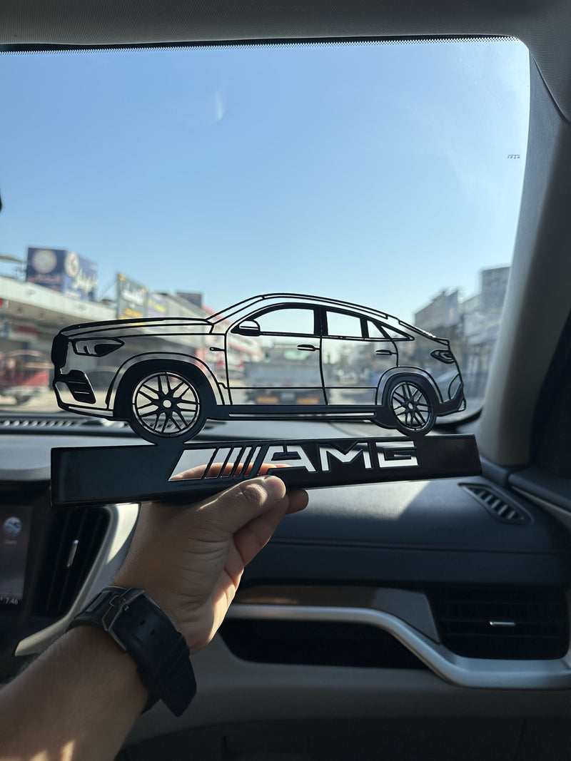 Hand holding a car decal with 'AMG' branding inside a vehicle.
